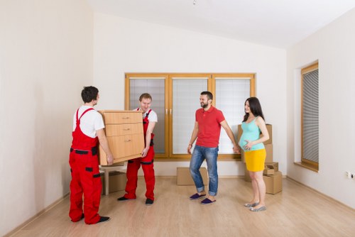 Removal crew navigating stairs during a flat relocation in Ilford